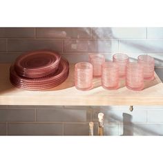 pink glasses and plates on a shelf in a kitchen