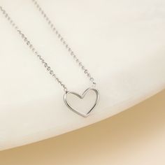 Our Heart Necklace is the epitome of understated elegance, offering a subtle yet powerful expression of love in its simplest form - a heart. This dainty heart necklace, featuring the delicate outline of a heart on a fine but sturdy chain, is more than just a piece of jewelry; it’s a symbol of the enduring nature of love in all its forms.Designed for versatility, this minimalist necklace seamlessly complements both casual and formal attire, making it a perfect choice for everyday wear or special Minimalist Heart Charm Necklace With Cable Chain, Delicate Sterling Silver Heart Necklace With Clavicle Chain, Classic Heart-shaped Necklace With Cable Chain, Minimalist Heart Pendant Charm Necklace With Cable Chain, Minimalist Cable Chain Jewelry For Valentine's Day, Minimalist Double Heart Charm Necklace With Adjustable Chain, Minimalist Heart Charm Necklace With Adjustable Chain, Dainty Heart-shaped Charm Necklace With Cable Chain, Minimalist Necklace With Heart Pendant Detail