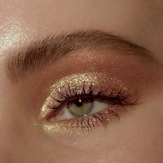 a woman's eye with gold glitter on it