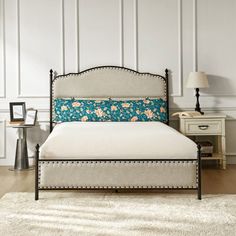 a white bed with blue and pink flowers on the headboard is in a bedroom