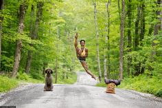 a woman is jumping in the air with her dog on the side of the road