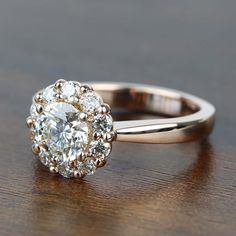 a diamond ring on a wooden table, with the center stone surrounded by smaller diamonds