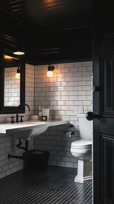 a white toilet sitting next to a sink in a bathroom under two lights on the wall