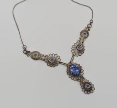 "This is a beautiful 1930 vintage necklace!  This is done in the Cennetille method of wire work.  It is ornate with twists and curls.  The large blue piece is a Czech glass piece with a flower.  Very pretty!  The other blue pieces are not glass. I have not tested the silver but I am assuming it is a low grade silver.  Very pretty unique piece.  It maintains it's original patina and I have not cleaned it. Neck length:  19\" long, pendant section 2\" long Condition:  good vintage condition, vintage patina Weight: 15.3 grams Please view enlarged photos for details and condition.  Much more beautiful in real life! I am not an expert on vintage jewelry, but I do buy and sell what I love! Since these items are vintage, they may have a wonderful aged patina and are not meant or expected to look b Antique Blue Filigree Necklace, Antique Blue Necklace With Intricate Design, Victorian Blue Filigree Necklace, Ornate Blue Necklace With Intricate Design, Handmade Victorian Blue Necklaces, Handmade Victorian Blue Necklace, Vintage Blue Filigree Jewelry, Blue Victorian Metal Jewelry, Vintage Metal Wire Wrapped Necklaces