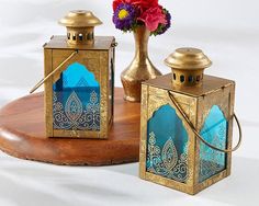 three small lanterns sitting on top of a wooden table next to a vase with flowers in it