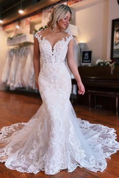 a woman in a wedding dress standing on a wooden floor