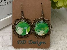 a pair of green earrings sitting on top of a card