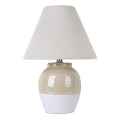 a white and beige ceramic table lamp with a light shade on the top of it