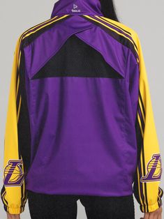 a woman wearing a purple and yellow jacket with the los angeles lakers logo on it