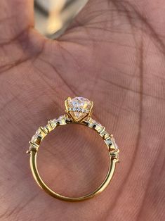 a close up of a person's hand holding a gold ring with diamonds on it