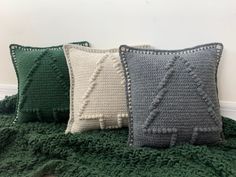 four knitted pillows sitting on top of a green blanket