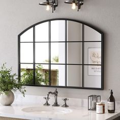 a bathroom sink with a mirror above it and a vase on the counter next to it