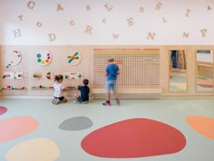 two children are playing in a playroom with colorful circles on the floor and walls