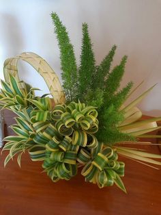 a vase filled with green plants on top of a wooden table