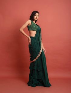 Dark green sequin and thread embroidered georgette blouse with attached soft organza ruffle at shoulder at the back, pre-pleated at center soft organza skirt with frill details and soft organza pre-pleated detachable pallu at waist and shoulder with gold lace embellishment.Dry Clean only. Green Organza Pre-draped Saree Traditional, Elegant Green Ruffled Pre-draped Saree, Embroidered Green Organza Pre-draped Saree, Green Embellished Semi-stitched Pre-draped Saree, Green Organza Embroidered Saree Fabric, Georgette Blouse, Organza Skirt, Ready To Wear Saree, Green Sequins