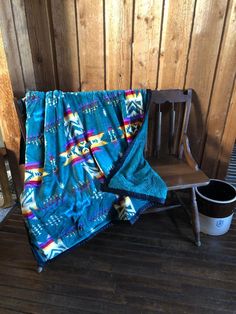 a wooden bench sitting next to a blue blanket on top of a wooden floor in front of a wooden wall