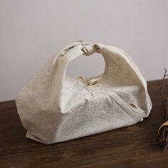 a white bag sitting on top of a wooden table next to dry grass and twigs