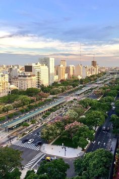 an aerial view of a city with tall buildings and lots of trees in the foreground