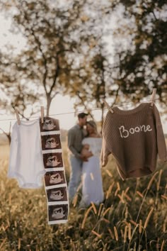 a couple is standing in the grass with their baby clothes hanging out to dry