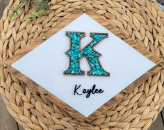 the letter k is made out of wood and has turquoise stones in it's center