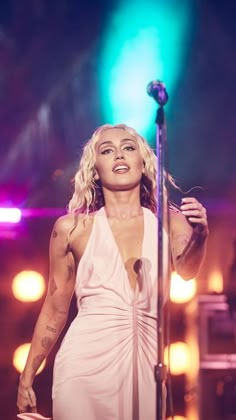 a woman in a white dress standing next to a microphone