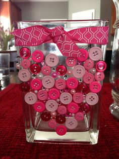 a vase filled with lots of pink buttons