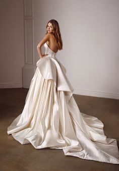 a woman in a wedding dress posing for the camera with her hands on her hips