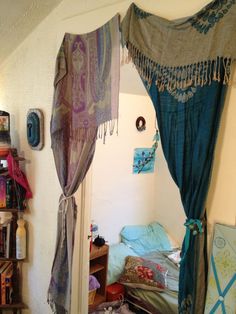 a bed room with a canopy and some pillows on the floor next to a book shelf