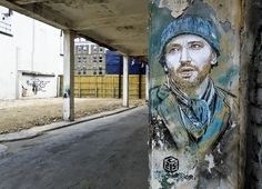 a man's face is painted on the side of a concrete structure under an overpass