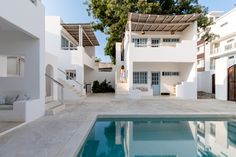 an empty swimming pool in front of two white buildings