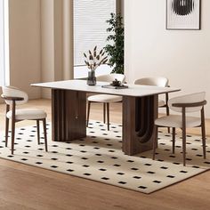 a dining room table with four chairs and a rug on the floor in front of it