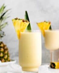 two glasses filled with pineapple smoothie on top of a table