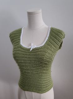 Introducing my handmade Crocheted Sleeveless Shirt - a stylish blend of comfort and elegance, meticulously crafted with care and expertise. This unique piece features a sleeveless design for a breezy and chic feel, perfect for warm days or layered looks. Our sizes go from XS to L, to fit as much as possible to a diverse spectrum of people according to my current time-frame and restrictions. The highlight of this stunning creation lies in its intricate details - a delicate crocheted ribbon that g Chic Fitted Crochet Tank Top, Elegant Cotton Sleeveless Blouse Vest, Elegant Sleeveless Sweater Vest For Summer, Green Cotton Vest Top, Fitted Green Sleeveless Sweater Vest, Green Fitted Sleeveless Sweater Vest, Green Tank Sweater Vest For Summer, Fitted Sleeveless Blouse For Beach, Elegant Sleeveless Cotton Vest