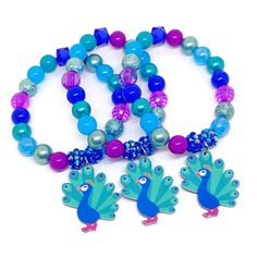 three bracelets with peacock charms and beads on white background, one is multicolored