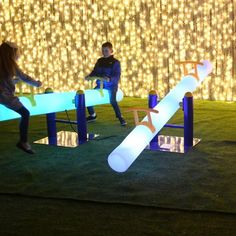 two people sitting on benches made out of fake snowboards and tubes with lights in the background