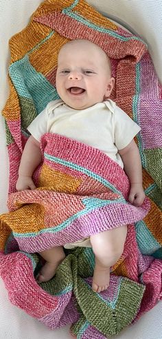 a baby laying on top of a colorful blanket