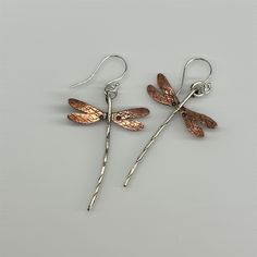 "Dragonfly earrings done in sterling silver & flame patinaed copper. Wings measure approx. 1\" wide and length including earwire is approx. 2 1/4 inch (give or take a bit on the length). Sterling earwires & dragonfly body, copper wings. Flame patina on the copper will vary! These have turned out to be one of my most popular earring creations! due to the hand made nature of these, each earring itself is individually made by hand, there may be slight variances between the photographs and the earri Unique Rust-colored Earrings With Ear Wire, Unique Rust Earrings With Ear Wire, Artistic Silver-colored Copper Earrings, Artistic Silver Copper Earrings, Unique Silver-colored Copper Earrings, Hand Forged Brown Earrings As A Gift, Rust Hand Forged Earrings As Gift, Hand Forged Rust Earrings As Gift, Hand Forged Silver Copper Earrings