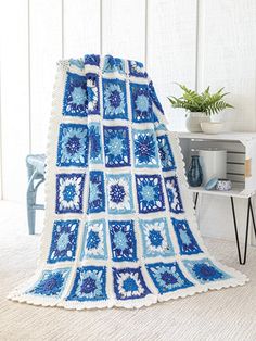 a blue and white crocheted afghan is on the floor next to a table