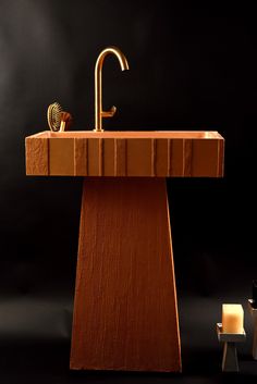 a sink made out of wood with a faucet in the middle and a candle next to it