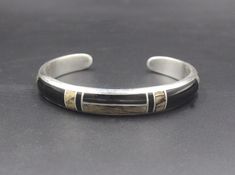 This is a solid sterling silver cuff bracelet with inlaid black onyx stone and spalted tamarind wood. Tamarind wood is an exotic tropical wood. Spalted tamarind wood has developed beautiful line patterns thru aging. The wood is sealed for protection. The bracelet width is 10mm. The gap is 1.25 inch for man's wrist size, 1 inch for woman's wrist size. Select your wrist size and we will make your bracelet to fit. Please measure your wrist size if you are unsure of the size. Sterling silver and sto Black Engraved Sterling Silver Bracelet As Gift, Classic Black Cuff Bracelet Bangle, Black Polished Cuff Bracelet For Formal Occasions, Classic Black Cuff Bracelet In Bangle Style, Black Engraved Sterling Silver Bracelet, Engraved Black Sterling Silver Bracelet As Gift, Formal Black Cuff Bracelet With Polished Finish, Engraved Black Sterling Silver Bracelet, Formal Black Polished Cuff Bracelet