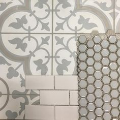 two white and gray tiles on the wall next to each other, one with an intricate design