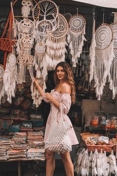 a woman standing in front of a display of dream catchers