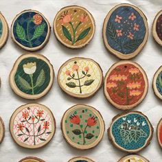 embroidered wooden slices with flowers and leaves are arranged on a white tablecloth covered surface