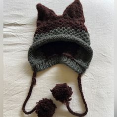 a knitted cat hat with two pom poms