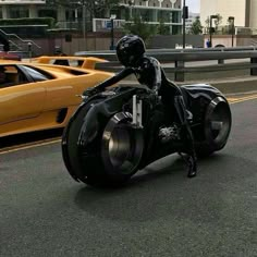 a person riding a motorcycle on the road with other cars behind them and one yellow sports car in the background