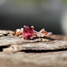 a pink diamond ring sitting on top of a piece of wood with diamonds around it