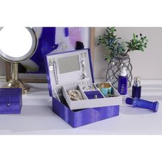 a purple box with jewelry inside sitting on a table next to a mirror and vase