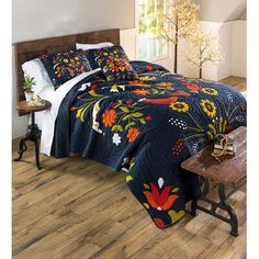 a bed in a room with wooden floors and a blue quilt on the coverlet