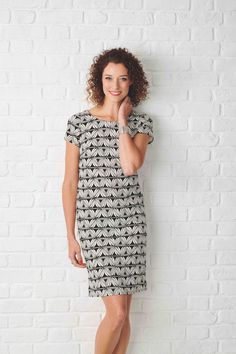 a woman standing in front of a white brick wall with her hand on her chin