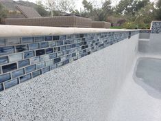 a blue and white tiled wall next to a swimming pool